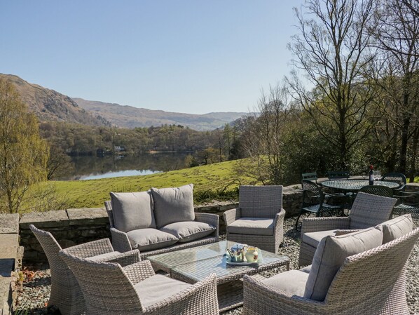 A patio with wicker furniture overlooking a lake and hills. - Huntingstile South (Ambleside)