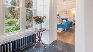 A room with a radiator, a white vase with flowers, and a blue sofa. - Huntingstile South (Ambleside)