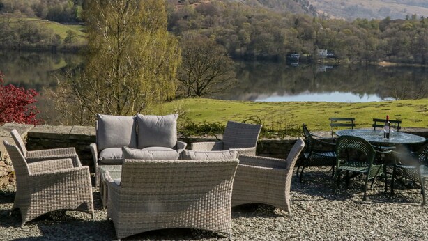 A patio with wicker furniture overlooking a lake and hills. - Huntingstile South (Ambleside)