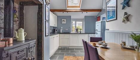 A kitchen with a wooden table, chairs, and a view through a skylight.