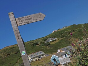 A wooden signpost indicating the Coast Path Public Footpath to Port Gavene, 5½m away.