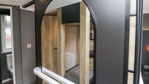 Een modern interieur met een houten vloer, een witte deur en een spiegel met een zwart frame.