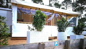Une cabane en bois à l’extérieur blanc, dotée de grandes fenêtres et d’un porche abrité.