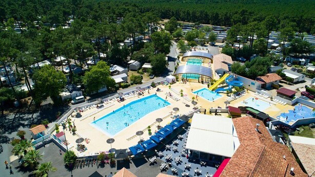 Vue aérienne d’un complexe hôtelier doté de plusieurs piscines, de zones de plage et d’un grand toboggan aquatique.