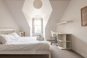 A bedroom with a bed, a desk, and a chair.