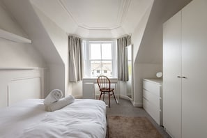 Een slaapkamer met een bed, een bureau en een stoel.