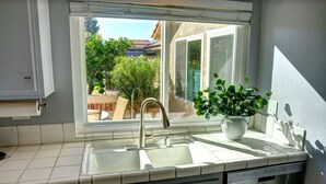 Eine Küche mit Fenster, Spüle und einem Blumentopf.
