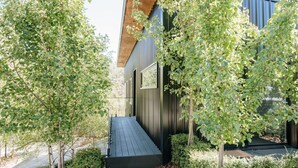 A modern building with a wooden deck and metal siding, surrounded by lush greenery. - Tree Top Haven ITAS - Hosted by L'Abode (South Launceston)