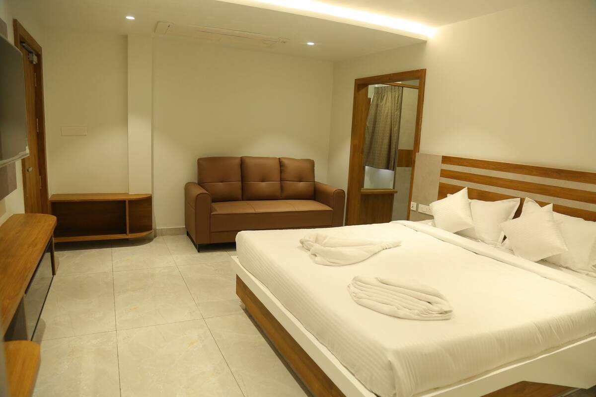 Una habitación de hotel con cama, sofá, televisor y espejo.