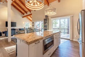 A spacious kitchen with a large island, stainless steel appliances, and a view to the outside.
