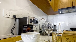 A modern kitchen with a coffee machine, a glass carafe, and a bowl on the counter. - Kilimani Bliss,Alba gardens studio apartment with a gym, infinity swimming pool (Nairobi)