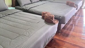 A hotel room with three beds, each with grey bedding and pillows, and wooden flooring. - Baan Thammarot View (Sirindhorn)