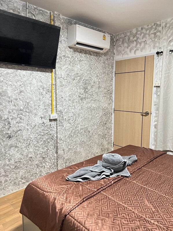 Une chambre d’hôtel équipée d’un lit, d’un téléviseur fixé au mur, d’un appareil de climatisation et d’une armoire.