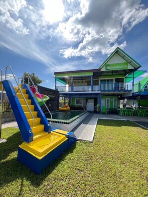 Un bâtiment doté d’une piscine, d’un escalier aux marches bleues et jaunes, et d’un toit végétalisé.