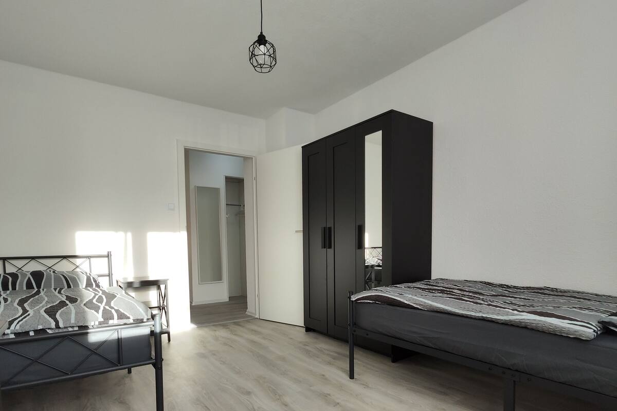 Um quarto com cama, guarda-roupa e escrivaninha.