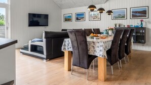 A modern dining area with a round table, black chairs, and a TV mounted on the wall.
