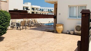A residential building with a patio area featuring outdoor furniture and a pool.