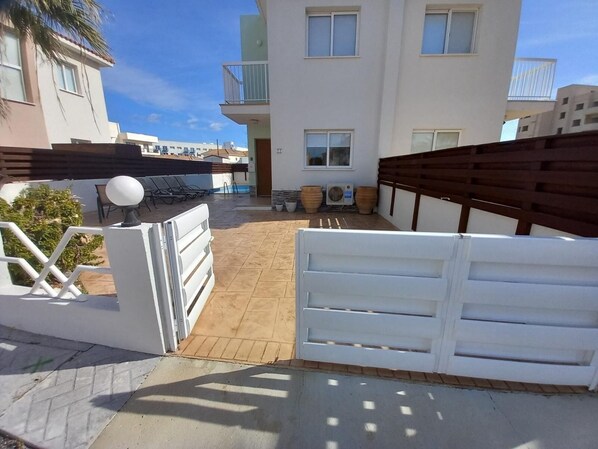 A gated courtyard with a pool, outdoor seating, and a view of neighboring buildings.