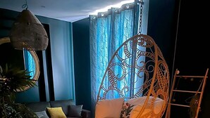 Una sala de estar acogedora con una silla colgante, un sofá, una mesa de centro y una chimenea.