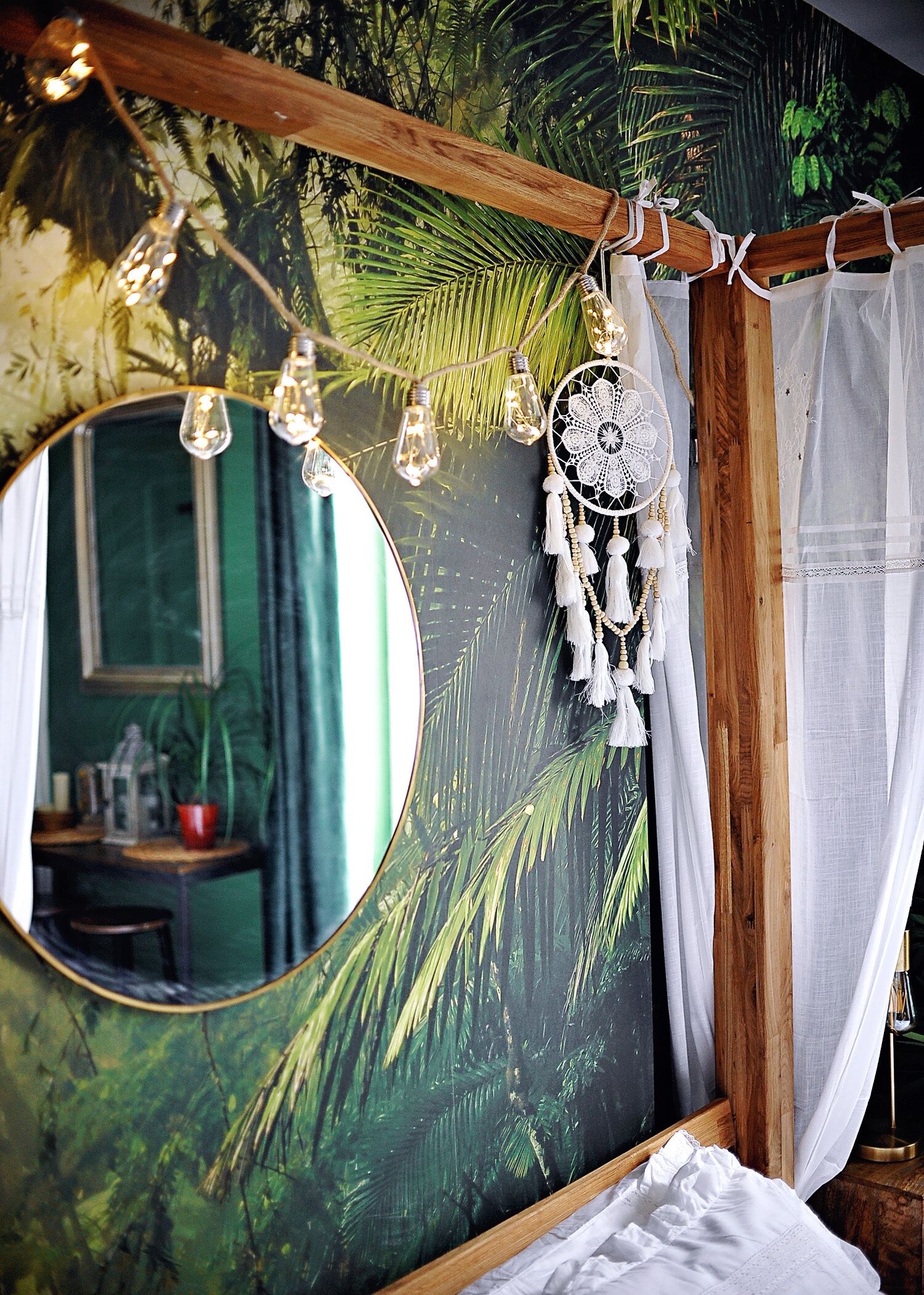Een slaapkamer met een grote spiegel, een droomvanger en een gordijn.