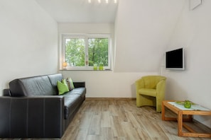 A modern living room with a leather sofa, a yellow armchair, a wooden coffee table, and a TV mounted on the wall.