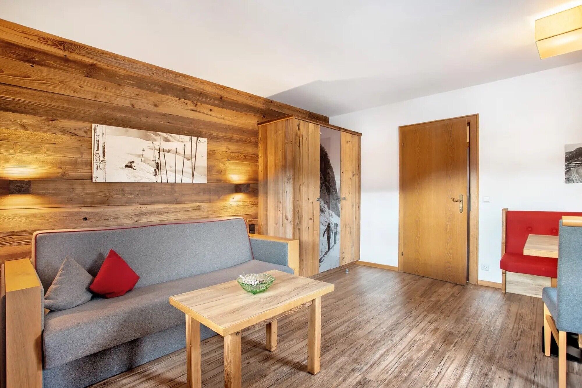 Une pièce avec un mur en bois, un canapé, une table et une porte.