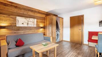 Une pièce avec un mur en bois, un canapé, une table et une porte.