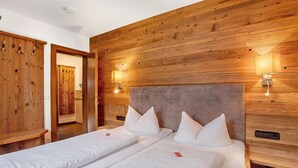 Een kamer met twee bedden, houten paneelwanden en wandlampen.