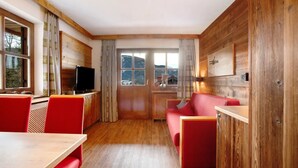 Une pièce chaleureuse avec un décor intérieur en bois, une télévision, un canapé rouge et une table.