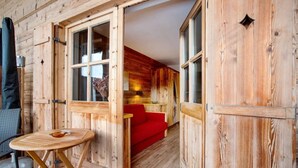 L’intérieur d’un chalet en bois comprend un coin repas, un canapé rouge et une cuisine ouverte.