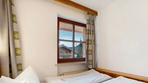 Une chambre avec deux lits, une fenêtre donnant sur un immeuble et des rideaux.