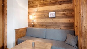 A wooden-paneled wall with a framed alphabet chart, a grey sofa, and a small wooden table.