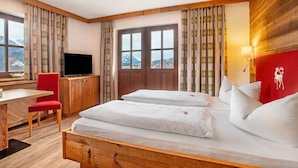 A hotel room with a bed, a desk, a chair, a television, and a window with curtains.