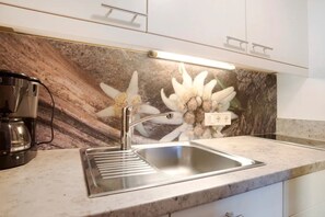 Una cocina con un lavamanos de acero inoxidable, una cafetera y un salpicadero decorativo.