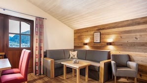 Ett mysigt rum med ett träpanelat tak, en soffa, ett litet bord och en stol.