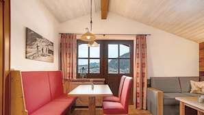 Ett mysigt rum med ett träpanelat tak, ett bord med stolar, en soffa och en divansoffa.