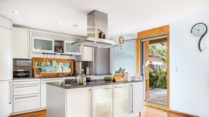 Eine moderne Küche mit weißen Schränken, einer Kochinsel und Blick auf eine Terrasse.