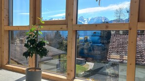 Ein Zimmer mit großen Fenstern, einem Blumentopf und Blick auf eine Berglandschaft.