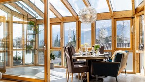 Ein moderner Essbereich mit Glaswand, Holzbalken und Bergblick.