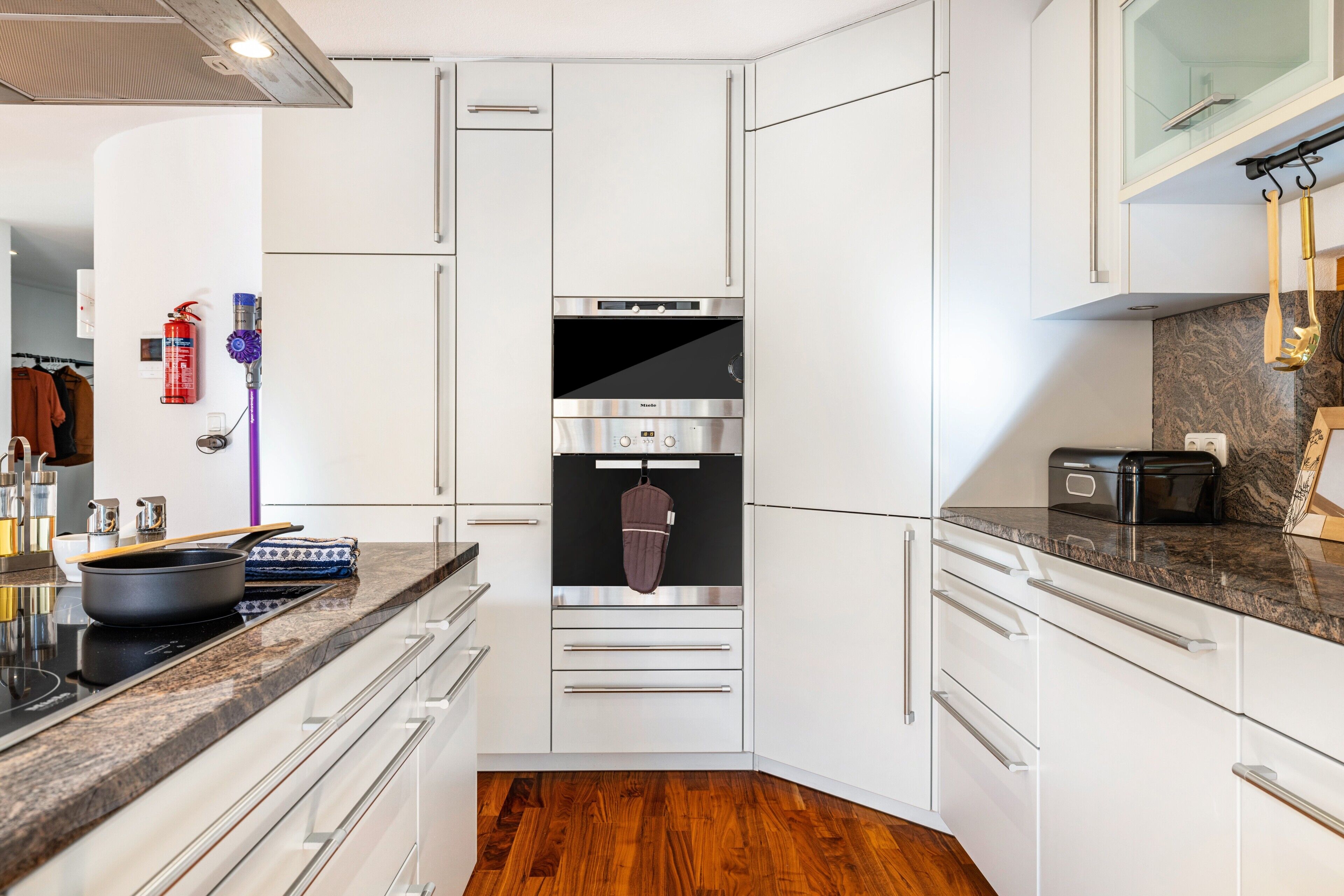 A modern kitchen with stainless steel appliances, white cabinetry, and a granite countertop.