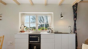 A compact kitchen with a window, built-in oven, and a sink. - Holiday Home 'Backhaus' with Mountain View, Private Terrace and Private Garden (Lauterbach)