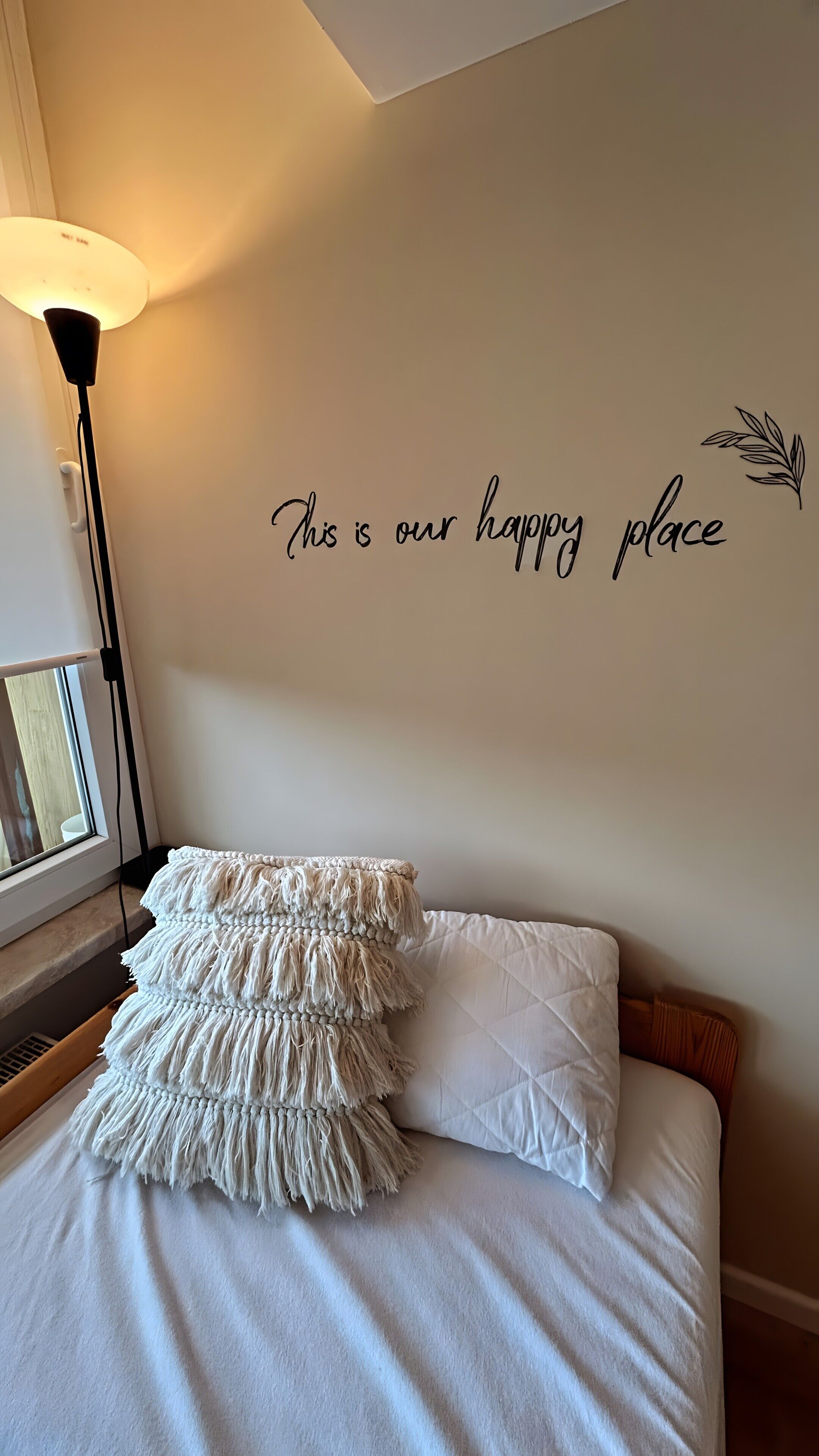 Ein Schlafzimmer mit einem Bett, einer Wandlampe und einem dekorativen Wandschild.