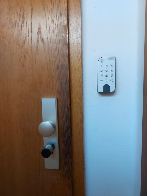 Una puerta con un ojo de cerradura y un teclado numérico fijado a la pared.