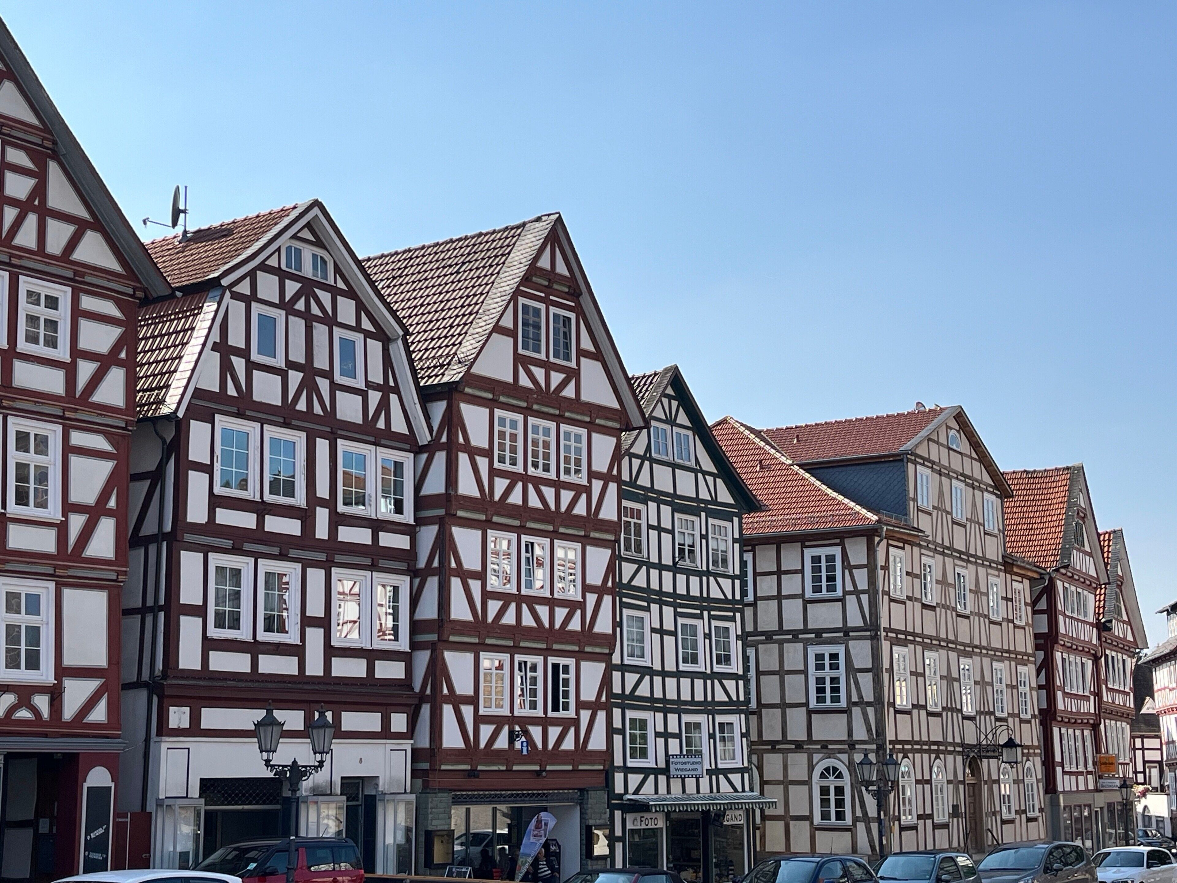 A row of traditional half-timbered buildings with visible shop fronts and a clear sky.
