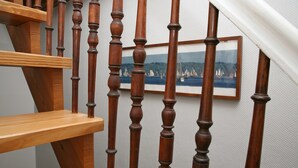 A wooden staircase with a framed painting of sailboats on the wall. - Apartment 'Mit Panoramablick' with Wi-Fi (Flensburg)