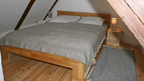 A loft-style bedroom with a wooden bed frame, a gray blanket, a bedside lamp, and a rug. - Apartment 'Mit Panoramablick' with Wi-Fi (Flensburg)