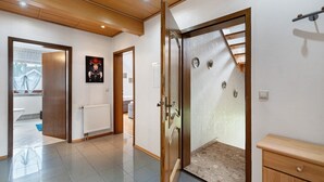 Ein modernes Interieur mit Holzbalkendecke, einer Glastür zu einem Badezimmer und einem kleinen Holzschrank.