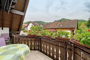 A balcony with a checkered table, wooden railing, and potted plants.