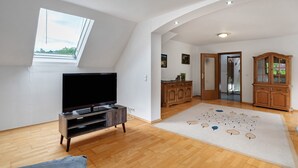 Ein Zimmer mit Fernseher, Holzschrank und Teppich mit Muster.