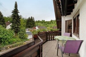 A balcony with a table and chairs, overlooking a garden and houses. - Apartment 'Serr' with Balcony and Wi-Fi (Lauf)